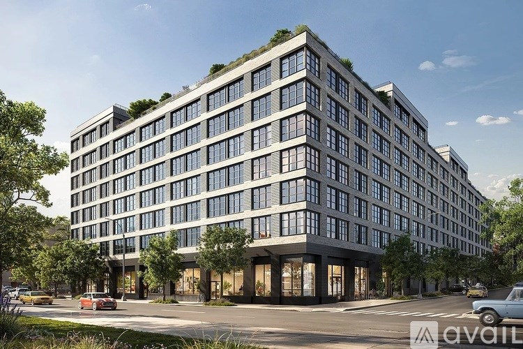 A modern multi-story building with a green roof and a parking lot in front.