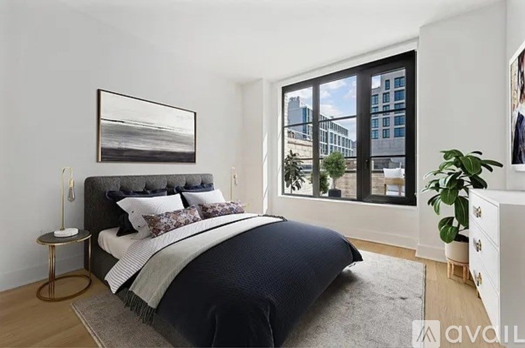 A bedroom with a large bed and a large window overlooking a cityscape.