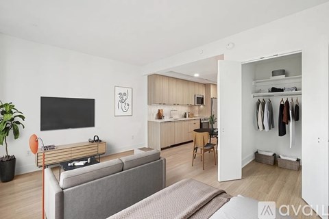A living room with a grey couch and a television on the wall.