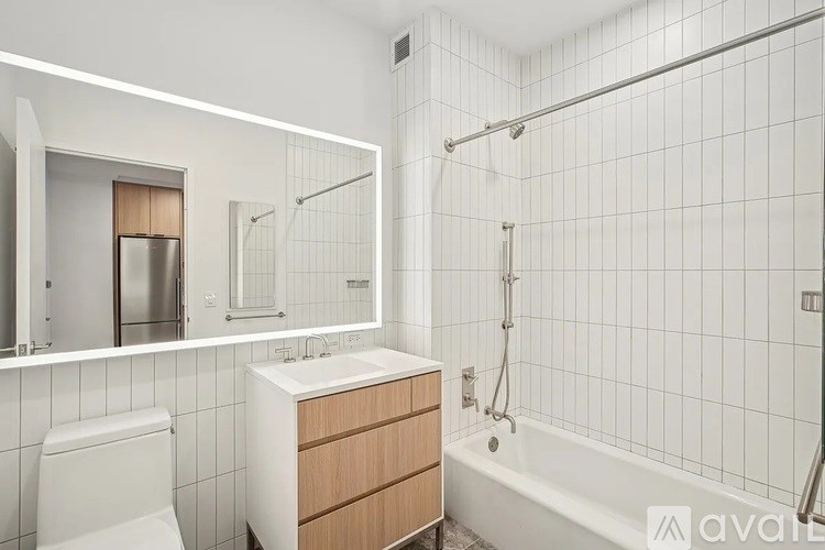 A white tiled bathroom with a toilet, sink, and bathtub.
