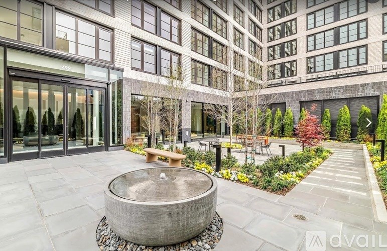 A courtyard with a fountain and benches in front of a building.