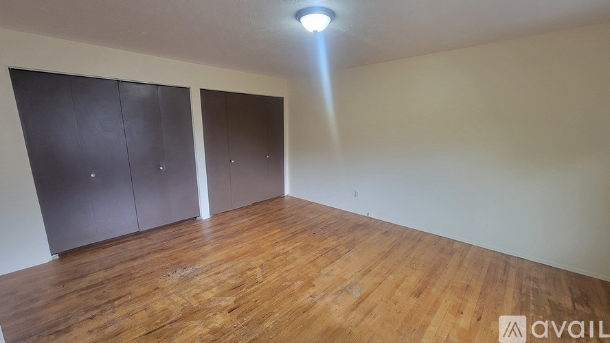 A room with wooden flooring and two dark brown closets.