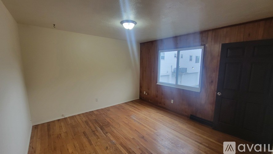 A room with wooden floors and a window showing a building outside.