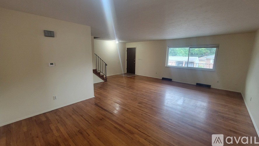 A room with wooden flooring and a window showing daylight outside.