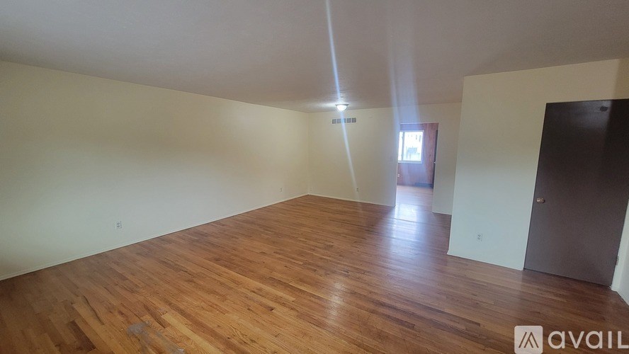 A room with wooden flooring and a door on the right side.