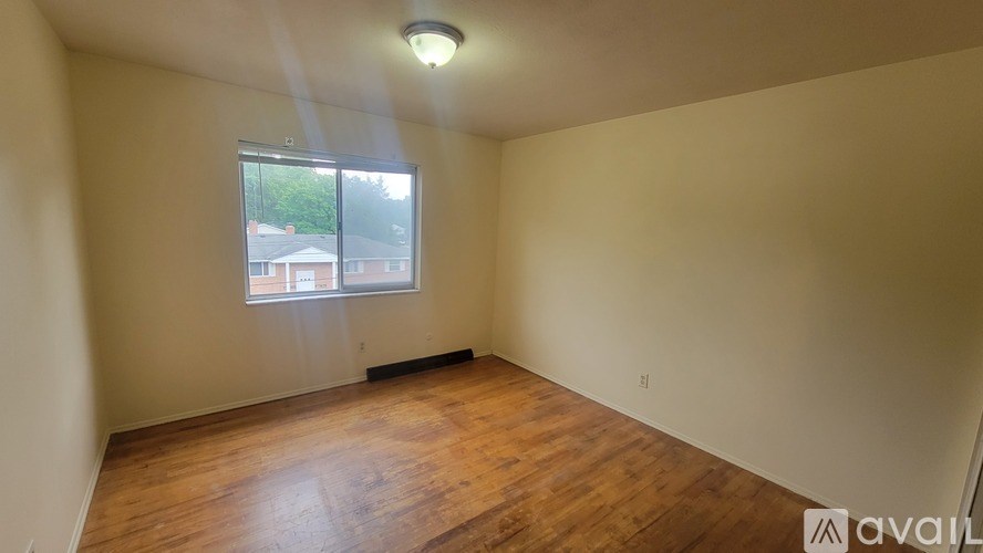 A room with wooden flooring and a window showing daylight.