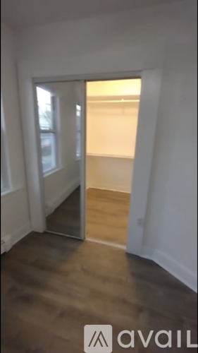 A room with a wooden floor and a doorway leading to another room.