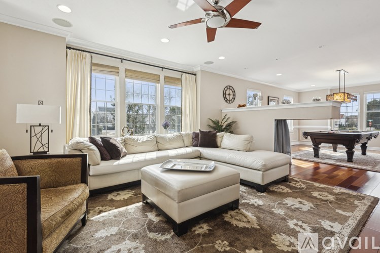 A living room with a white sofa, a brown patterned armchair, and a rug with a floral design.