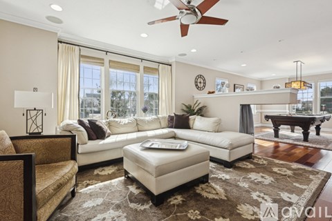 A living room with a white sofa, a brown patterned armchair, and a rug with a floral design.