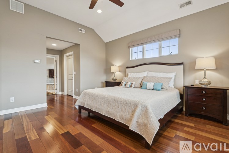 A bedroom with a large bed, wooden floors, and a ceiling fan.