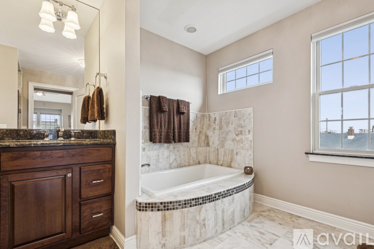 A bathroom with a marble tub surround and a window overlooking the water.