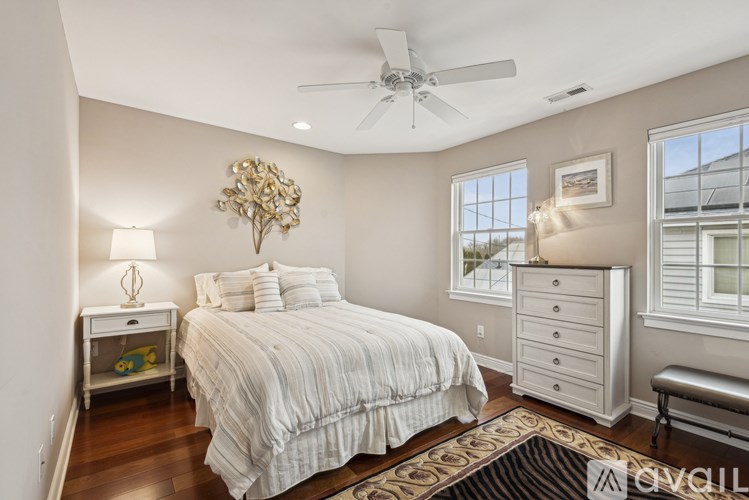 A bedroom with a large bed, a ceiling fan, and a window with blinds.
