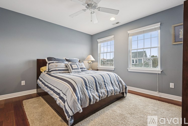 A bedroom with a bed, a ceiling fan, and a window.