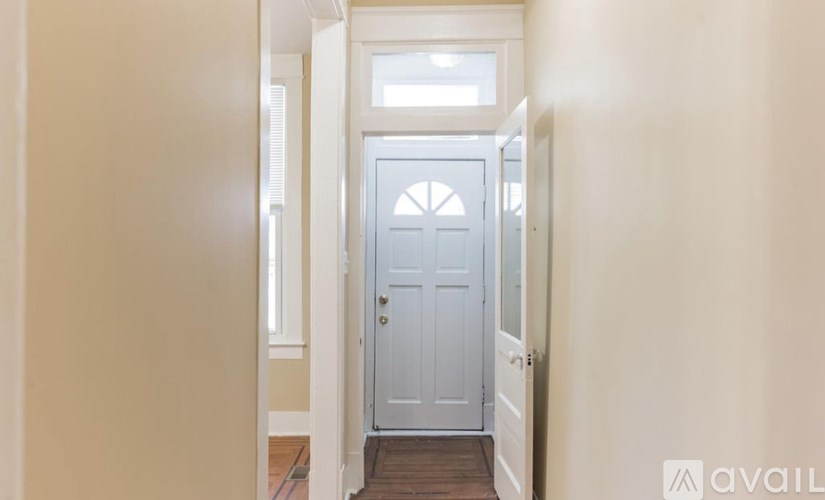 A white door with a window above it in a hallway.