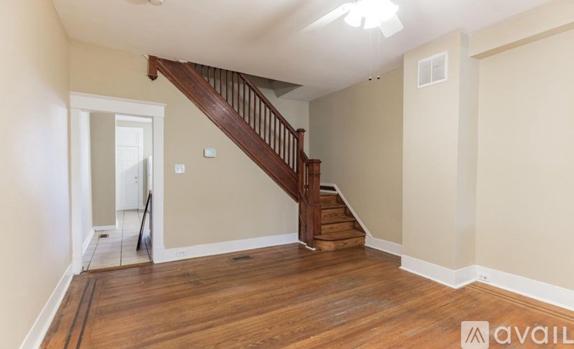 A room with wooden floors and a staircase leading to another room.