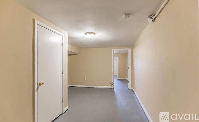 A room with a white door and a grey floor.