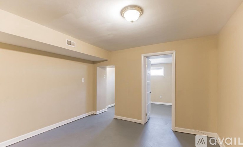 A room with beige walls and a grey floor is available for rent.