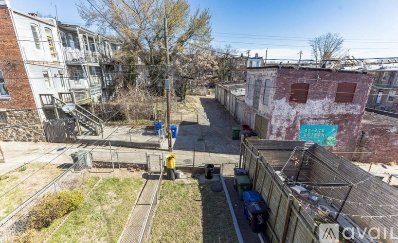 A view of a backyard with a train track and a building with a blue sign.