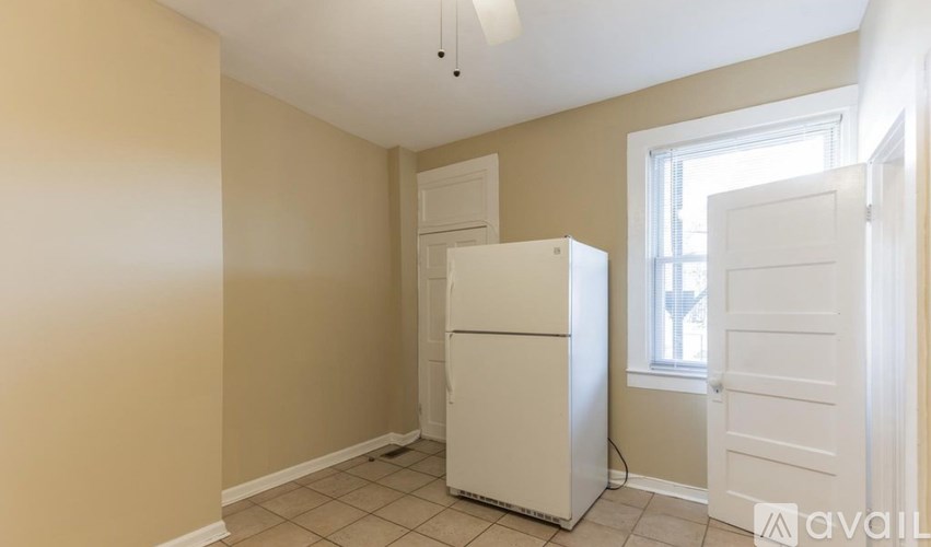 A white refrigerator is in a room with beige walls.