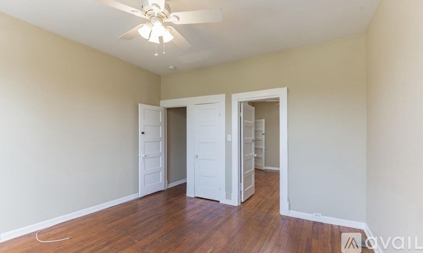 A room with a ceiling fan and wooden floors.