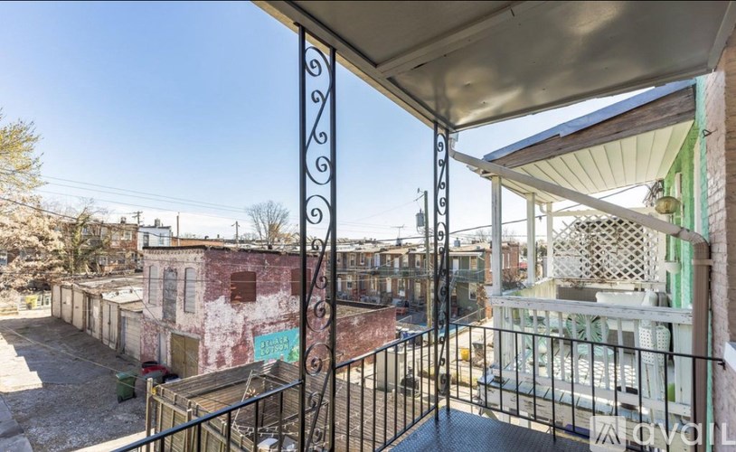 A balcony with a metal railing and a view of a building and trees.