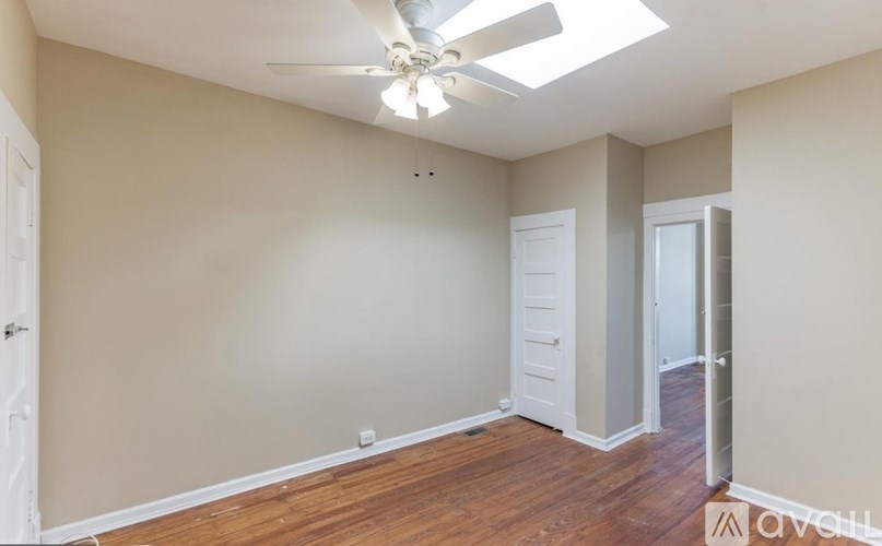 A room with a ceiling fan and wooden floors.