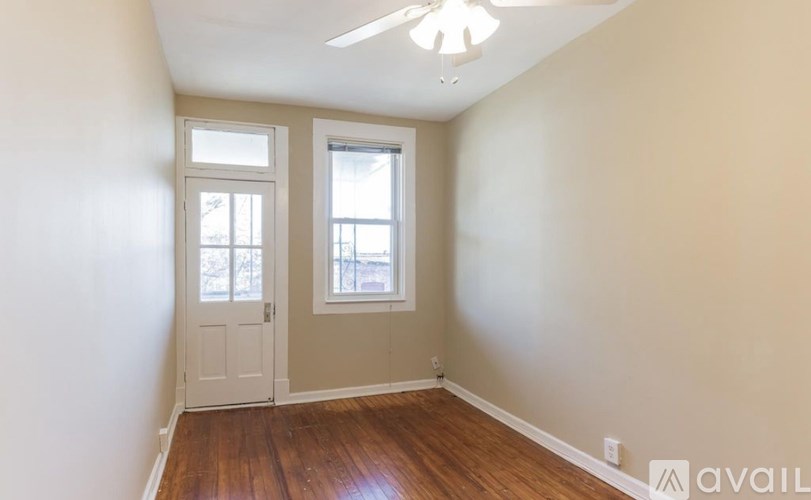 A room with a white door and a window with a view of trees.