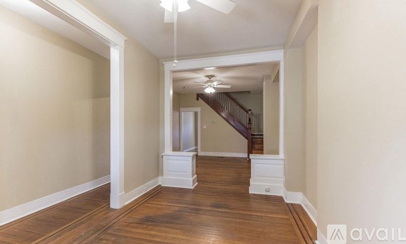 A long hallway with a staircase on the right and a door on the left.