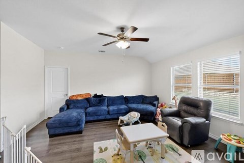 A living room with a blue couch and a ceiling fan.