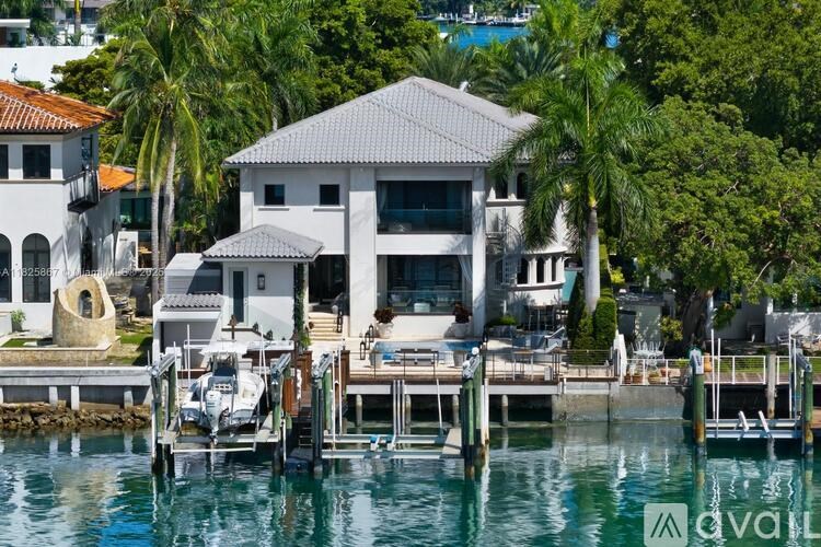 A white building with a black roof is situated on a dock with a boat in front of it.