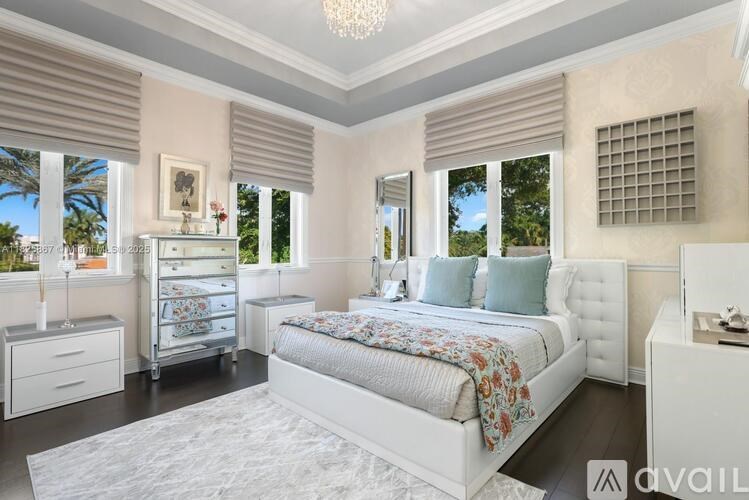 A bedroom with a large bed, a chandelier, and a window with blinds.
