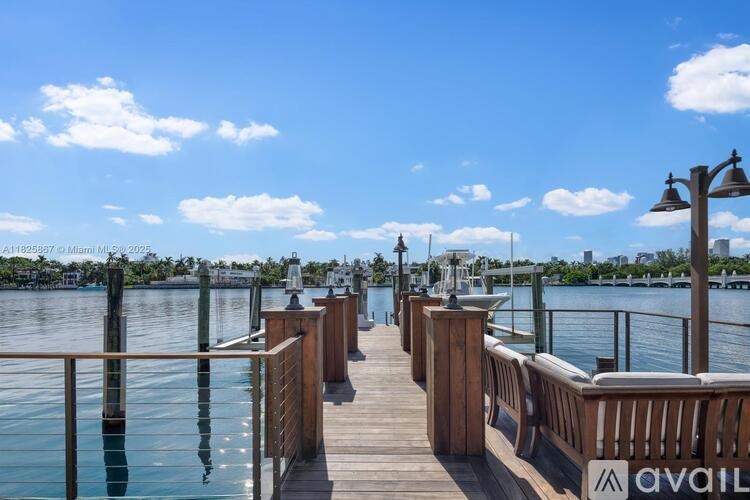 A wooden pier extends into a body of water with a clear blue sky above.