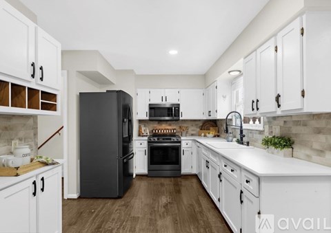 A modern kitchen with white cabinets and a black refrigerator.