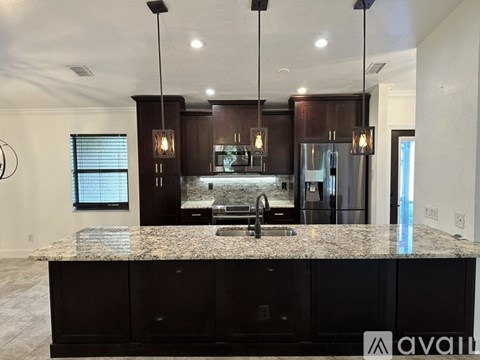 A kitchen with granite countertops and dark brown cabinets.