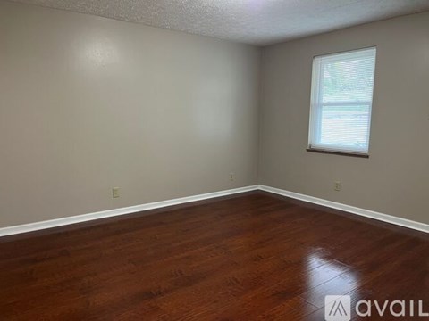 A room with a window and wooden flooring.
