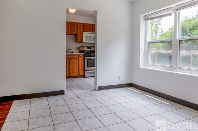 A kitchen with white tiled floors and wooden cabinets is visible through an open door.
