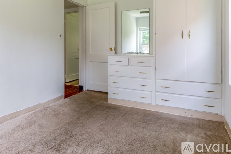 A bedroom with a white wardrobe and a brown carpet.