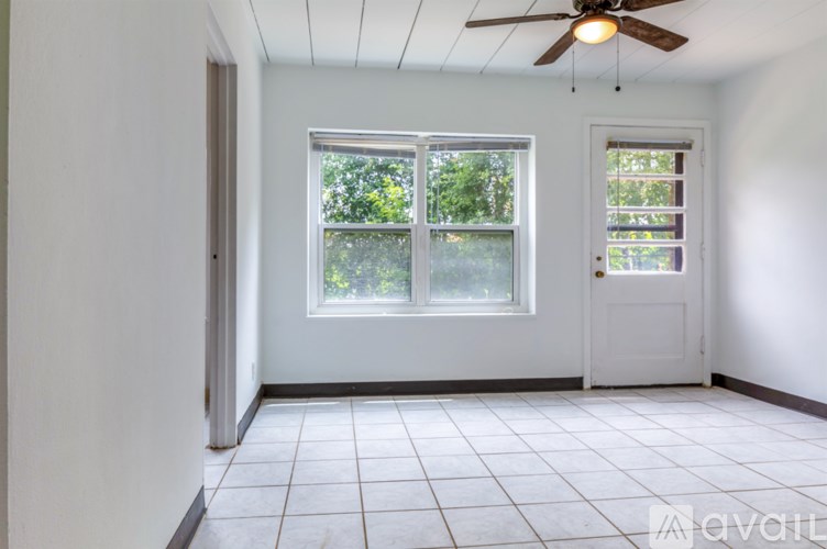 A room with a ceiling fan and two windows.