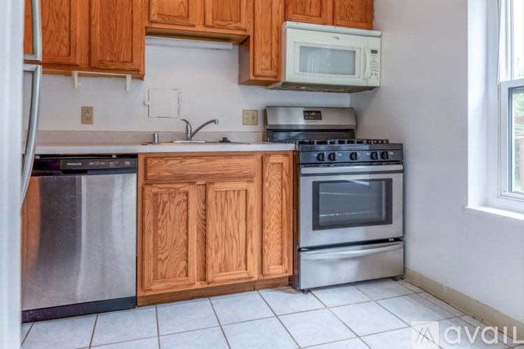 A kitchen with wooden cabinets and a stainless steel dishwasher.