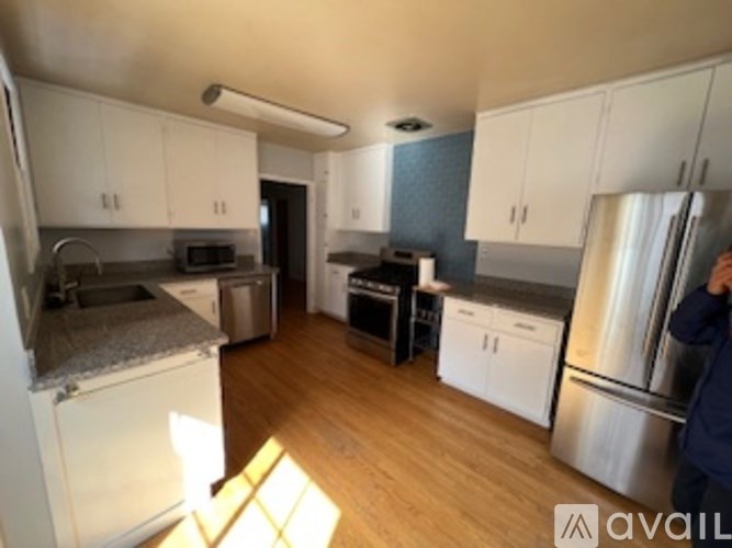 A kitchen with white cabinets and a refrigerator.