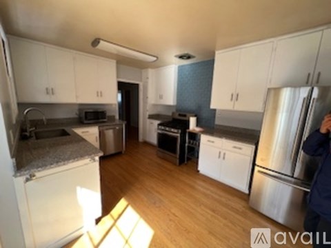A kitchen with white cabinets and a refrigerator.