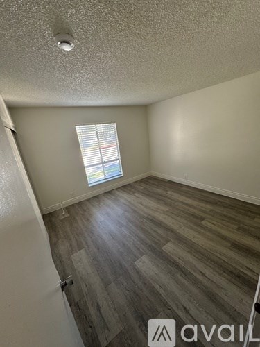A room with wooden flooring and a window with blinds.