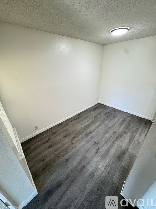 A room with wooden flooring and white walls.
