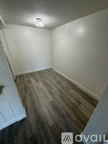A room with wooden flooring and white walls.
