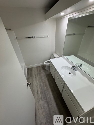 A bathroom with a toilet, sink, and mirror.