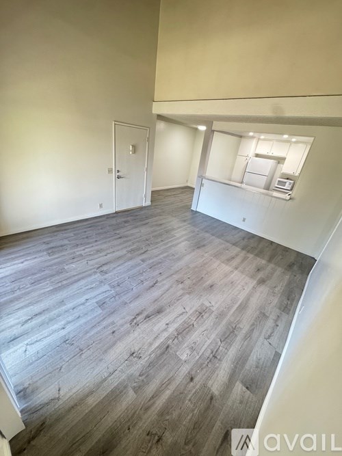 A room with a wood floor and a window with blinds.