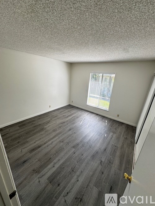 A room with wooden flooring and a window on the left side.