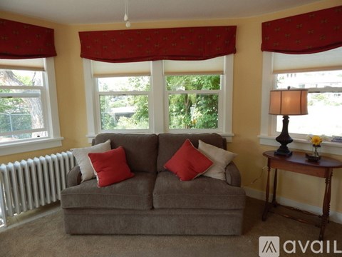 A living room with a grey couch and red pillows.