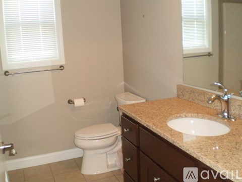 A bathroom with a toilet, sink, and a window with blinds.