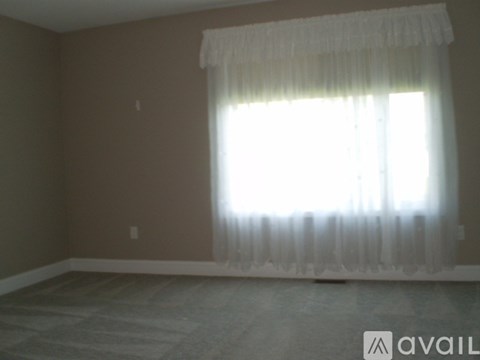 A room with a window covered by a white curtain.